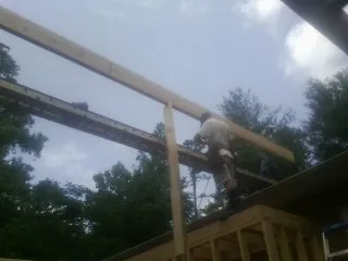 Carpenter setting a ridge beam over a new addition frame — Ice Dam Removal by Roofing Brothers in Flora