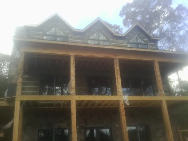 Dormers and porch framing on a large log home under construction — Roof Coating work by our crew in Flora