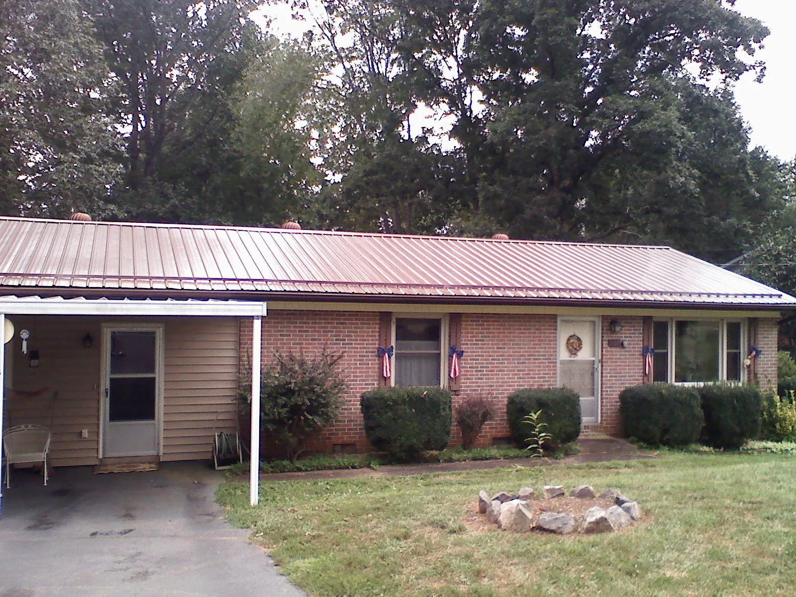 Bronze metal roof and carport on a brick ranch home — Roof Repair work by our crew in Flora